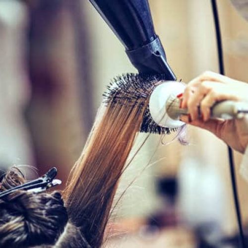 Professional hairdresser drying hair, in ctudio