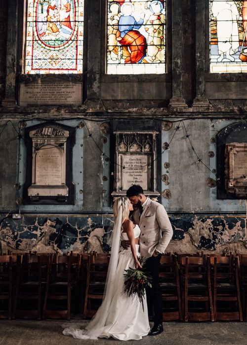 cool, modern bride and groom in old church with natural makeup and soft curly hair
