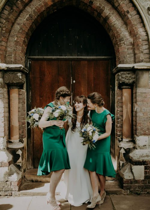 happy bride boho outside a church in london with her two bridesmaids