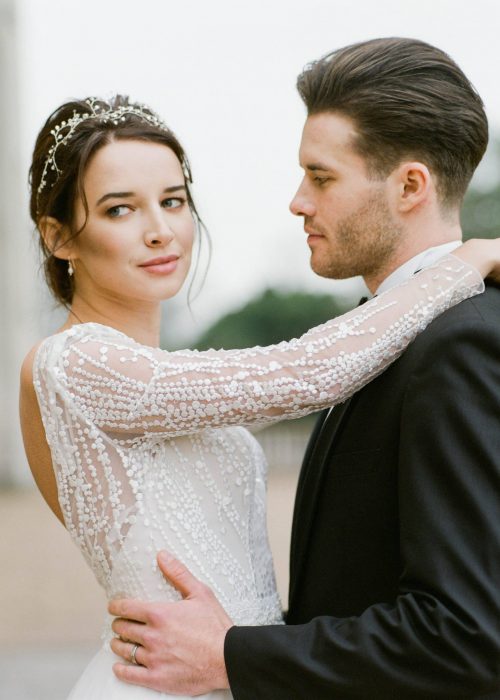 bride and groom together. Bride hair up and groom holding her waist. Makeup is natural and soft with a neural lip